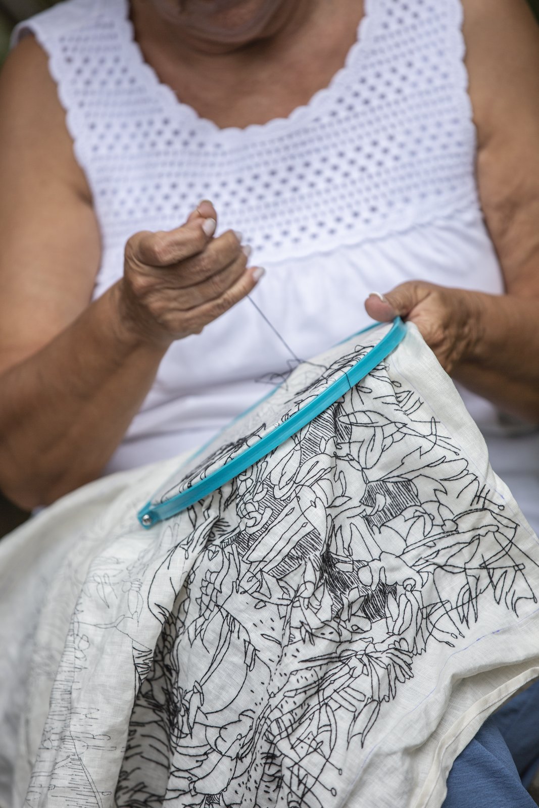 An older woman's hands and hoop, held close to her chest