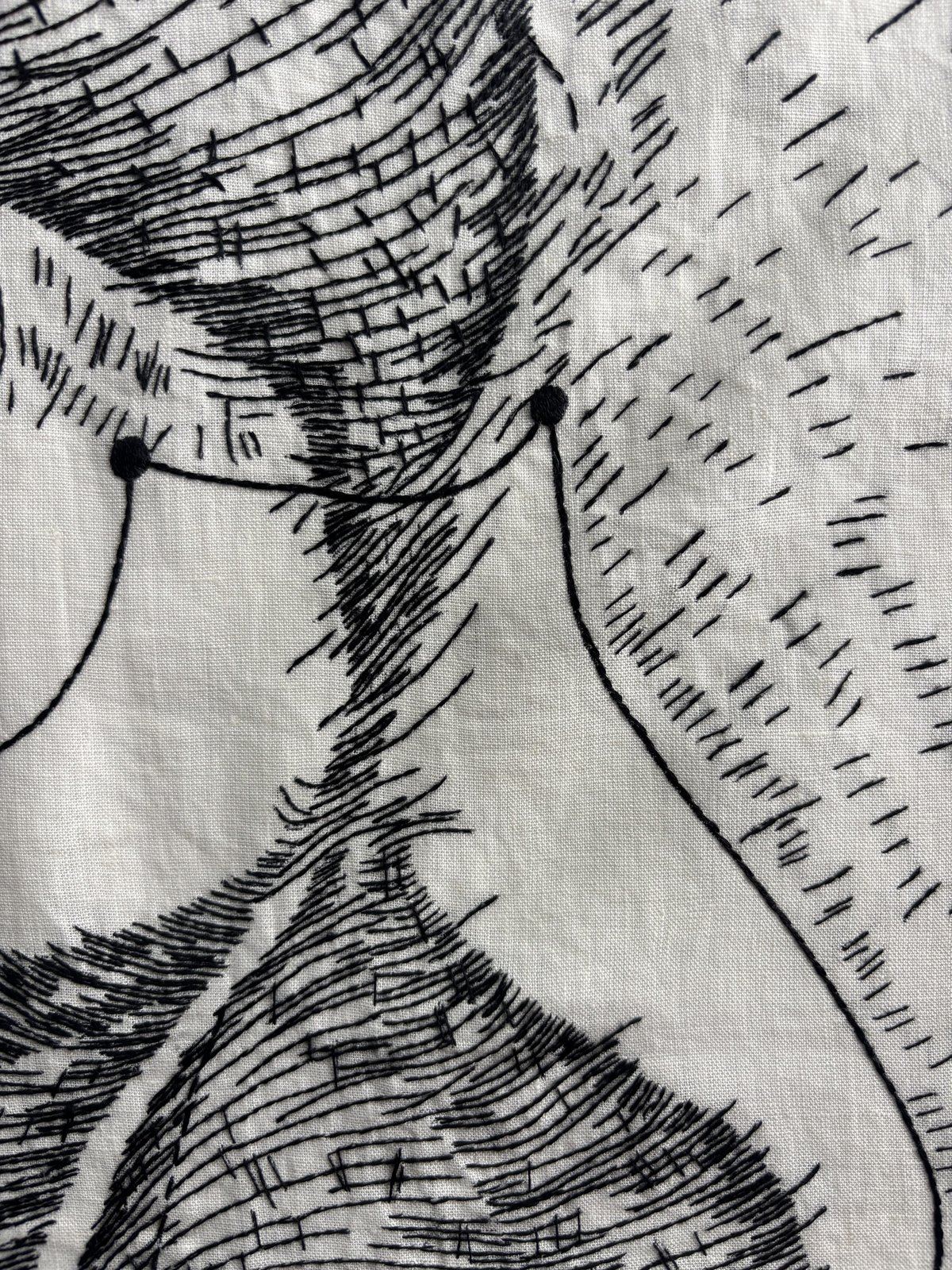 Close detail of dense black-thread hatching on linen