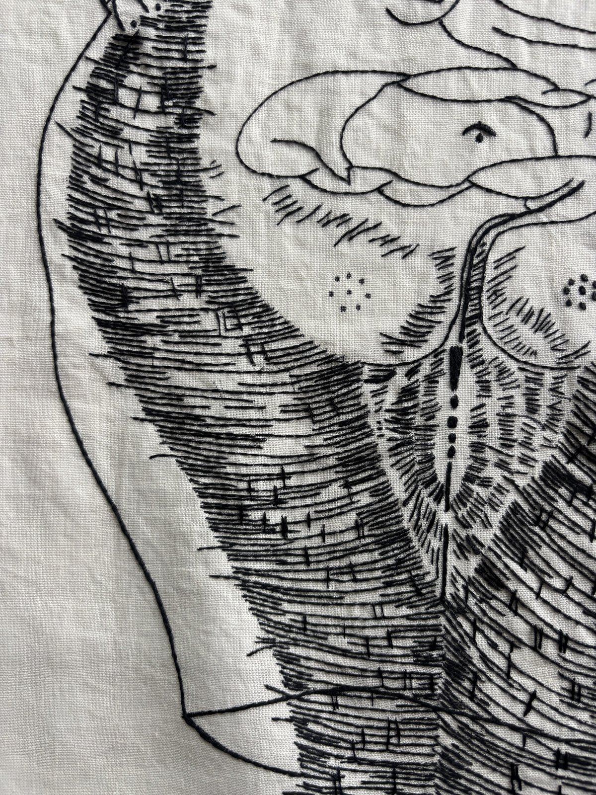 Close detail of a stitched form, eye and feathering visible