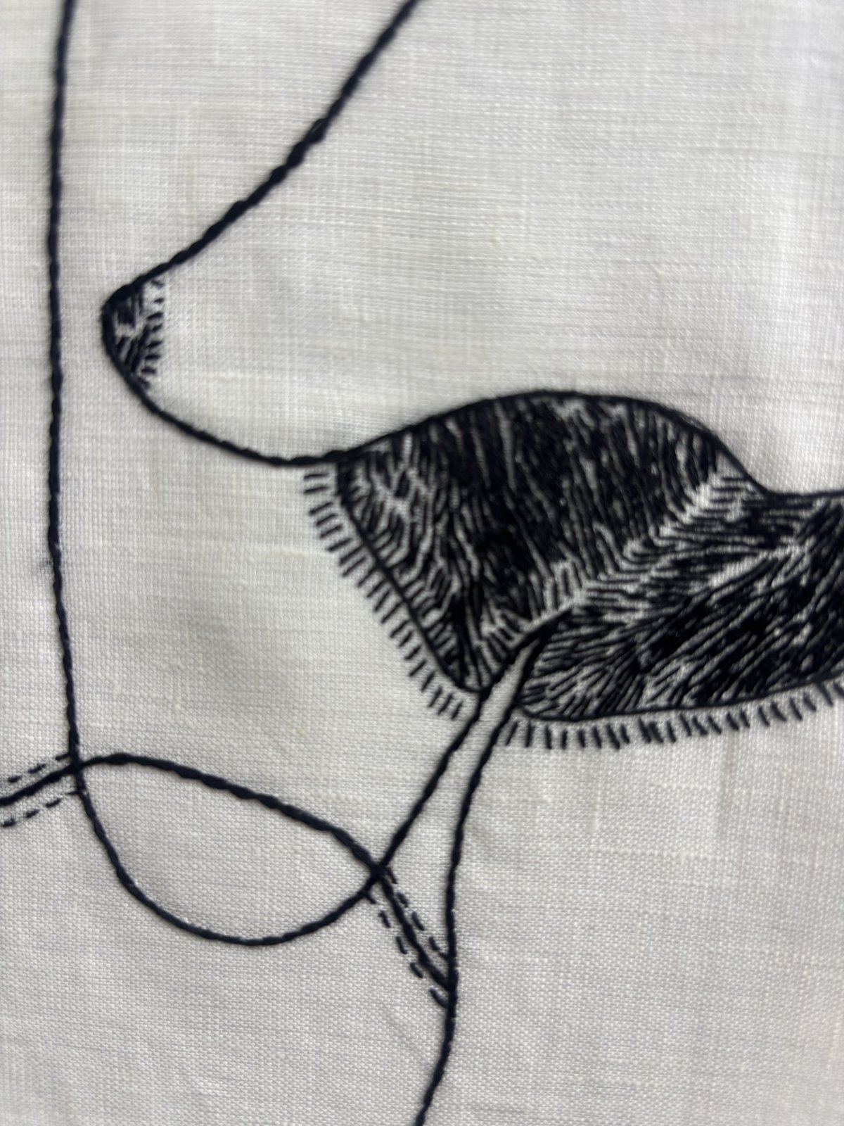 Close detail of a single filled stitched form against bare linen