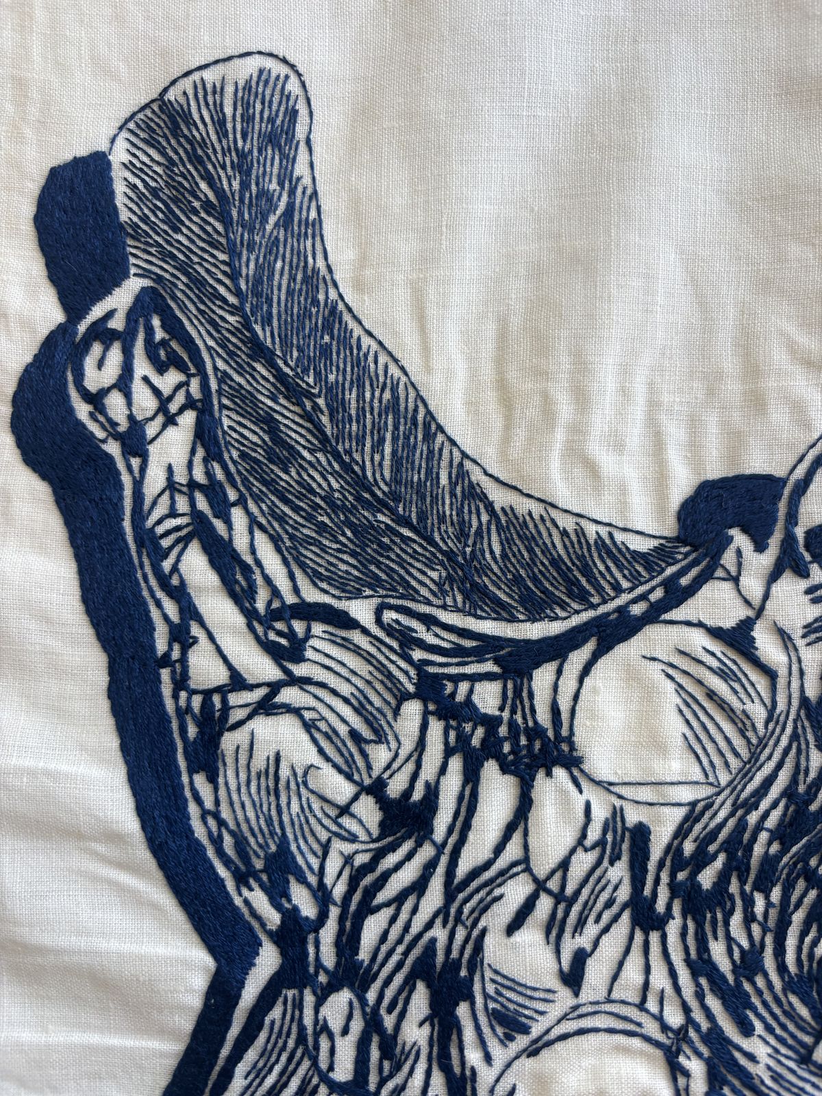 Close detail of navy-thread stitching, curved feather form