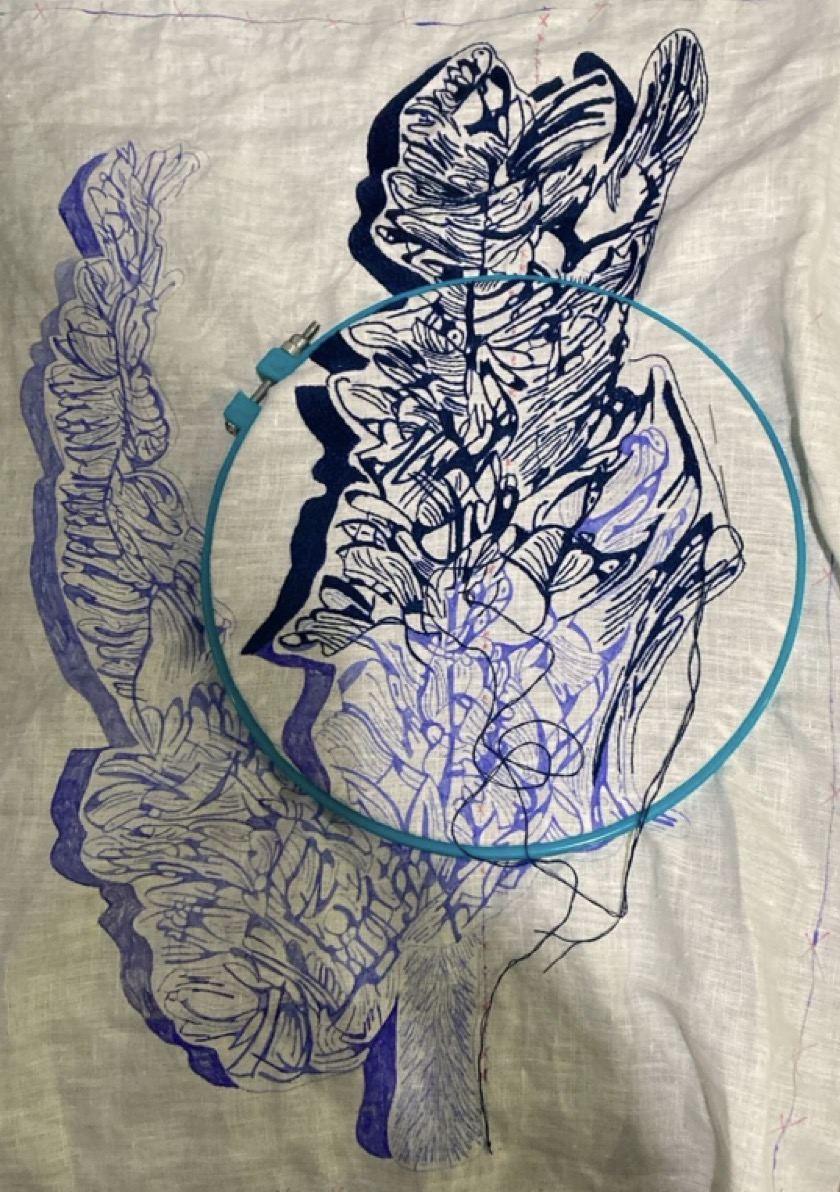 Blue-marker design sketched on linen, hoop over the pattern